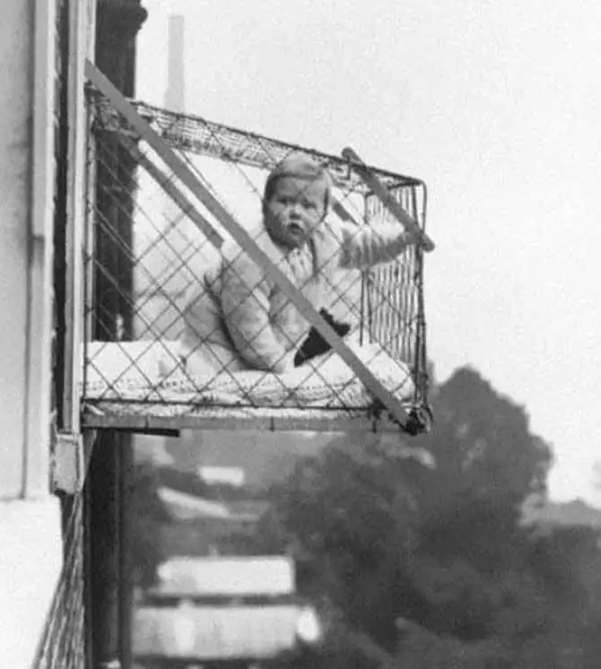 A Photo Of A Baby In A Cage Hanging Out An Apartment Window - 10 Eerie Photos That Will Send Shivers Down Your Spine