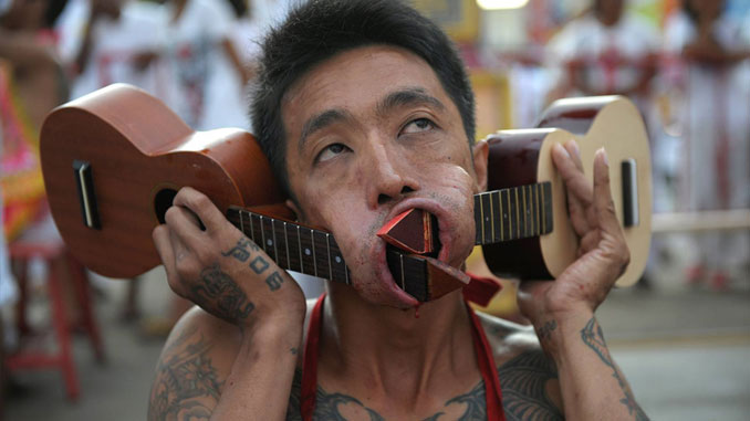 Man with guitars through his cheeks at the Vegetarian Festival in Thailand - 10 Most Insane Body Modifications You Just Have To See