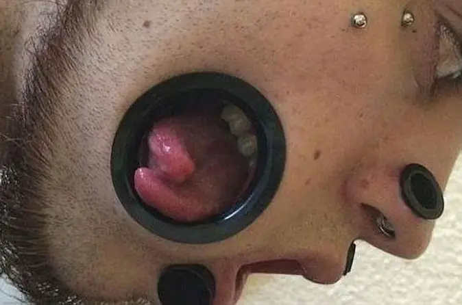 Joe Miggler showing his cheek holes - 10 Most Insane Body Modifications You Just Have To See