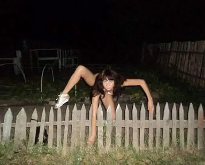 A creepy looking girl climbing over a fence - 20 WTF Photos You Just Have To See