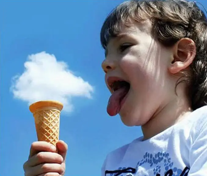 A boy that looks like he is holding an ice cream made of clouds.
