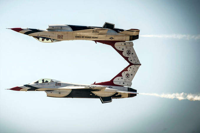 Two US AIr Force jets flying, one is upside down.