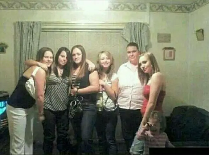 A mysterious photo of a group of girls with a ghost peering out from behind their legs.