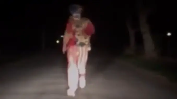 Creepy clown filmed running at a car.