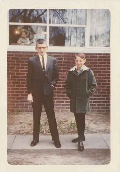 Two brothers standing next to each other in an old family photo, but is there a ghost in the window?