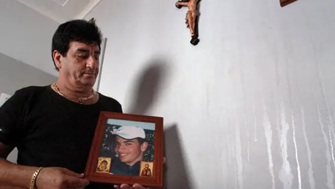 George Tannous holding a photo of his dead son, Mike, next to the miracle oil weeping from wall. Truly a paranormal mystery