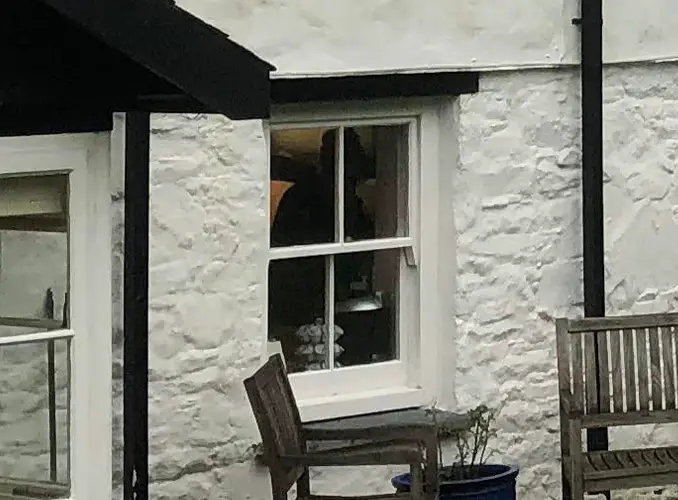 Close up photo of old house with mysterious cloaked figure in the window.